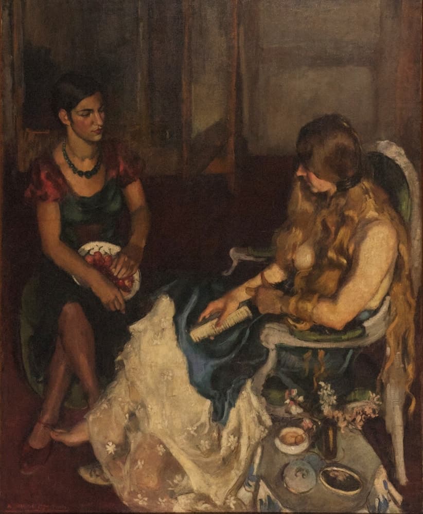 Two young women in a dark red-brown room. On the left a dark-haired woman in a green dress with crimson sleeves and a green bead necklace sits upright on a green chair, legs crossed, holding a white plate of red cherries in her lap. On the right a fair-haired woman sits slumped in a white-framed chair, her long hair falling over her face and bare torso, holding a white comb over blue cloth; a white embroidered shawl spills from her lap to the floor. A low grey table at the lower right holds a saucer, a vase of pink and white blossom, a round box and an oval gold-rimmed object like a hand-mirror