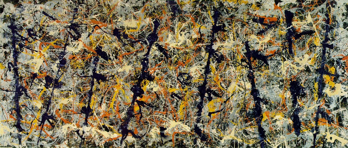 A canvas nearly five metres wide in which eight dark blue-black bars lean across a dense silver-grey field, each reaching almost the full height and tilted slightly left or right. Around them run tangerine-orange lines, bright cadmium yellow, thick cream pools, thin white threads and a separate tangle of black lines. The signature Jackson Pollock 52 reads at the lower left