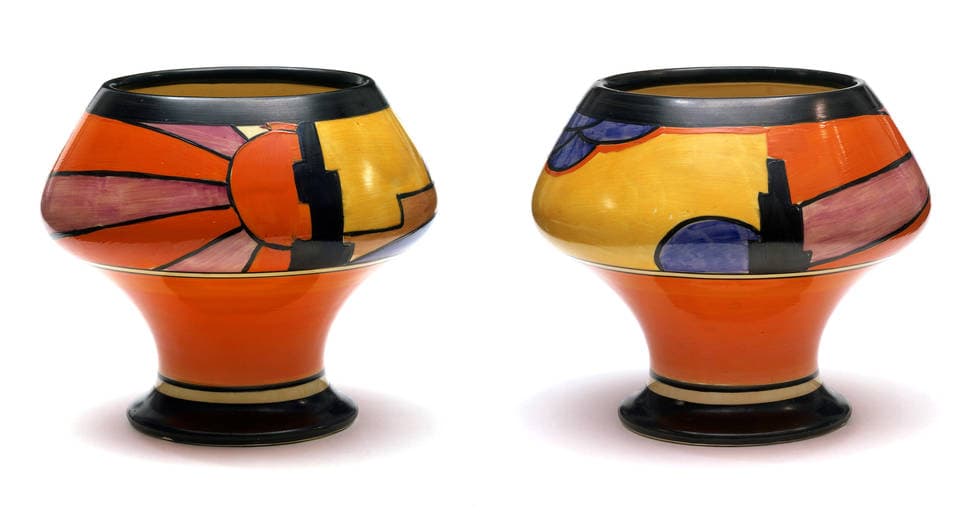 Two views of the same vase side by side, each with a broad upper body narrowing to a flared foot. The front shows a half-disc sun in orange and red throwing straight rays across yellow and pink panels; the reverse shows dark blue half-discs against orange and yellow. Both carry a black band at the rim, black outlines between colours, and a stepped black form at the right.