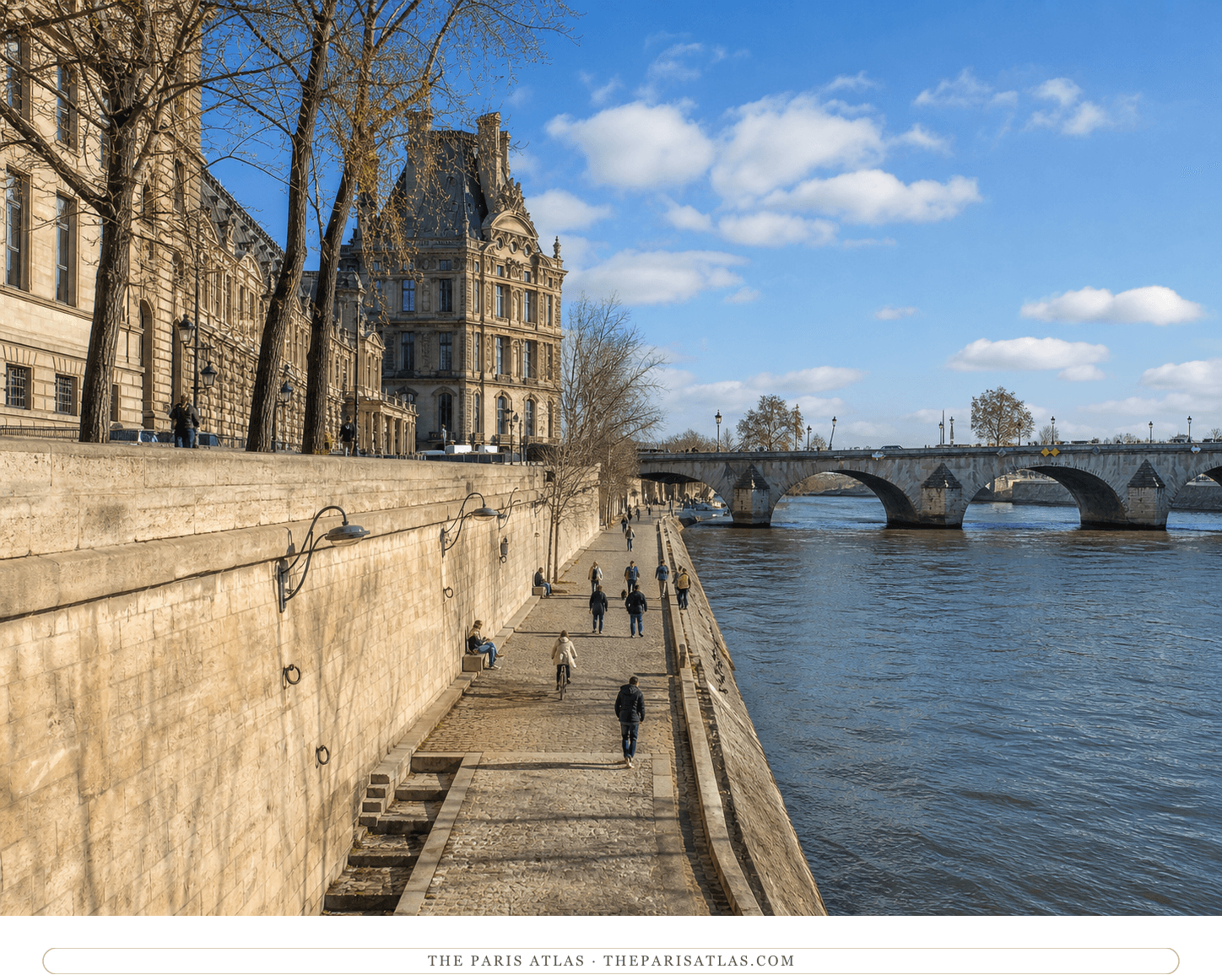 Walkers and a cyclist on the sunny lower quay beside Pont Royal