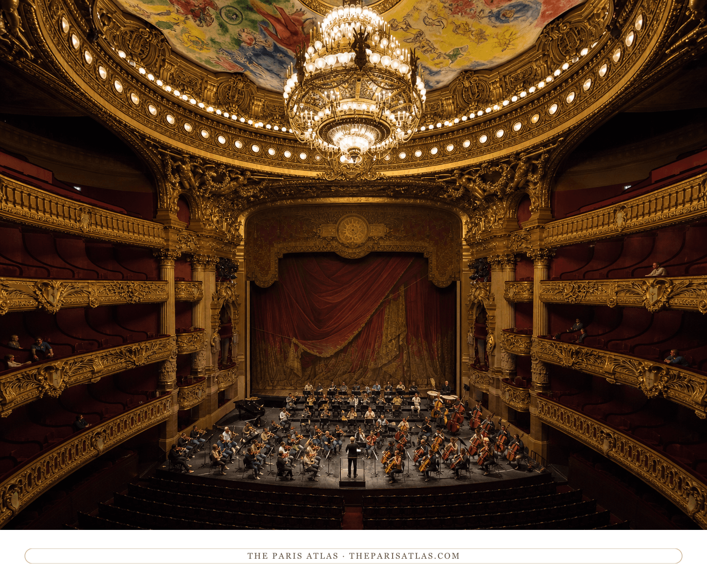 An orchestra rehearsing onstage beneath the chandelier and Chagall ceiling in the Palais Garnier auditorium