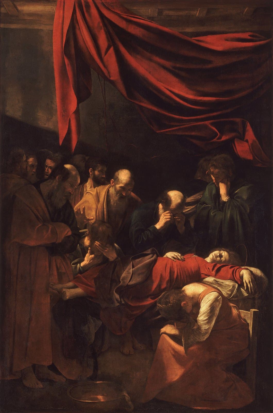 A dead woman in a red dress lies on a low bed with one arm hanging down and her bare feet exposed, a thin gold halo above her head. Barefoot men in brown and dark robes crowd around her weeping and covering their faces, and a young woman sits doubled over in grief at the foot of the bed. A large red curtain is bunched across the top of the picture