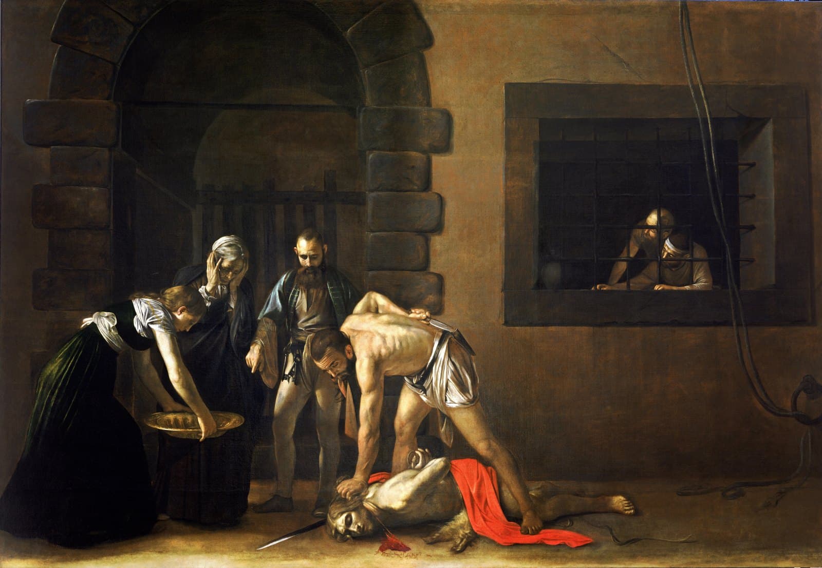 In a bare prison yard a half-naked man kneels over a body on the ground, gripping its hair and reaching behind him for a knife at his belt to finish cutting off the head. A young woman bends forward holding out a brass basin, an old woman beside her clutches her own head, and a jailer points down at the basin. Two prisoners watch through a barred window on the right. Blood runs from the severed neck across the pale ground