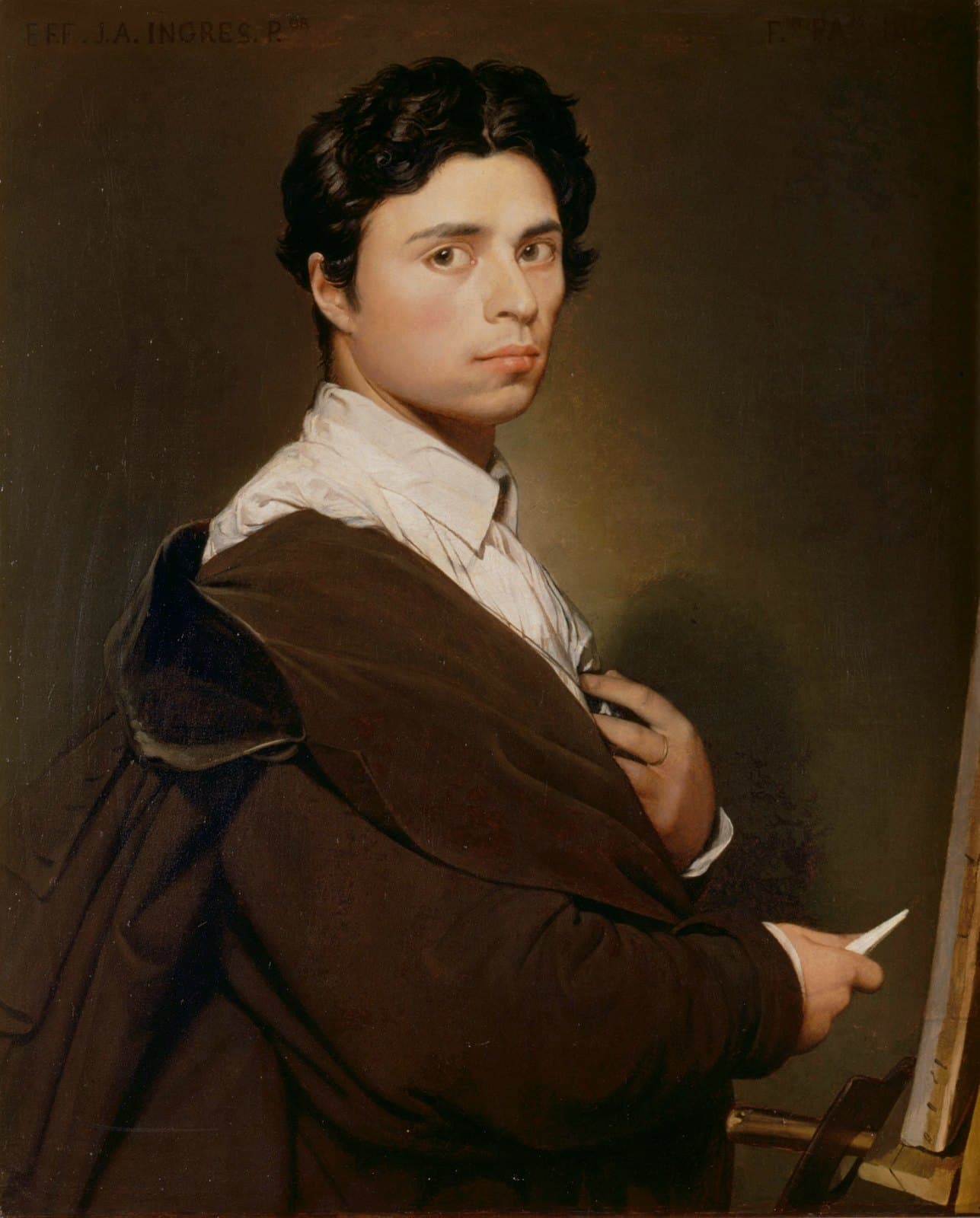 Self-portrait of a dark-haired young man in a dark coat at an easel, turning toward the viewer with chalk in hand