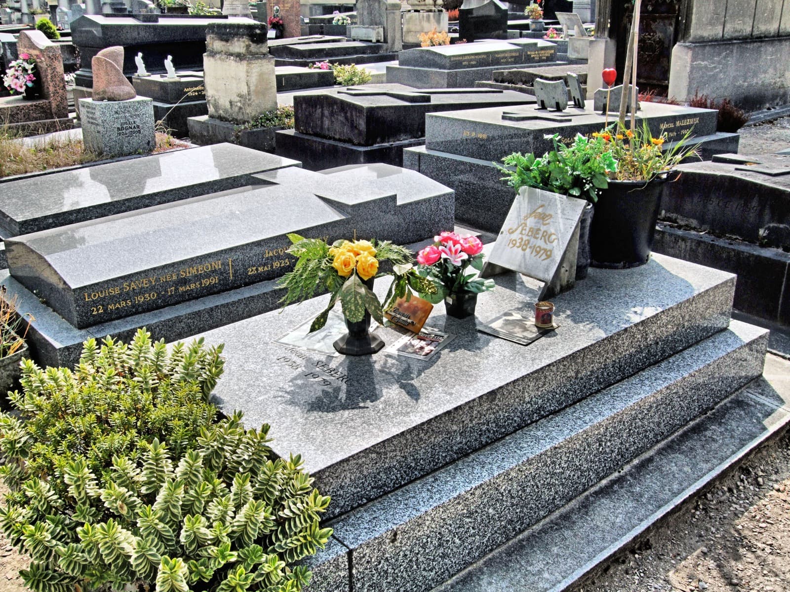 Jean Seberg's flat gravestone in Montparnasse Cemetery, covered with visitors' flowers and Métro tickets