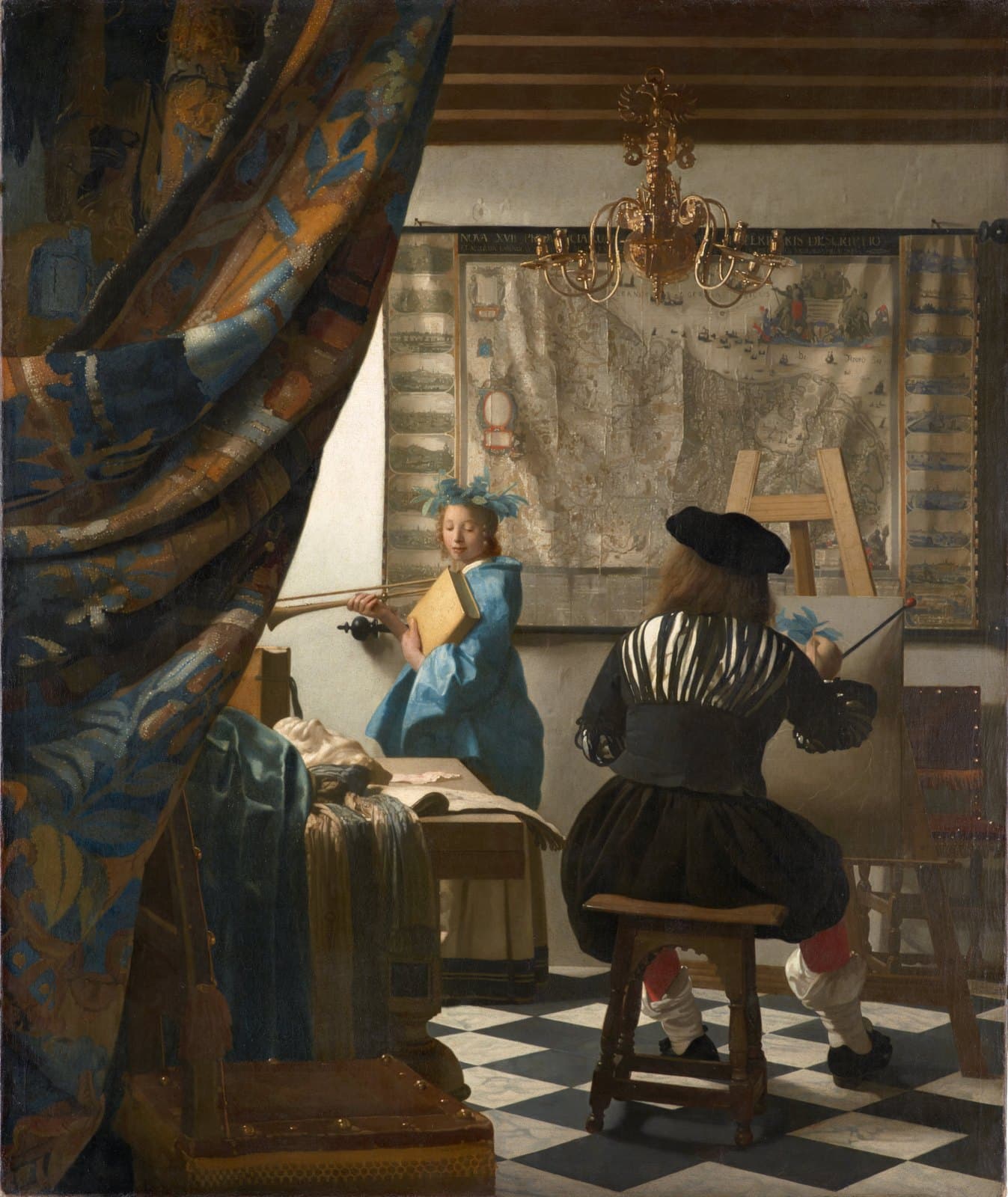 A painter in a black slashed doublet sits with his back to the viewer at an easel, painting a young woman who stands by a window in a blue dress with a laurel wreath, a trumpet, and a book. A large map hangs on the back wall, a brass chandelier hangs above, and a heavy curtain is drawn back at the left.