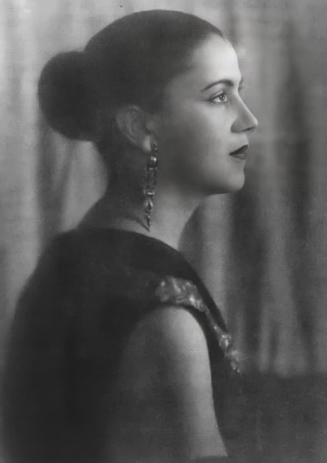 Studio portrait of Tarsila do Amaral in her late thirties, seated and turned slightly to one side, in a dark dress with a short bobbed haircut, looking away from the camera
