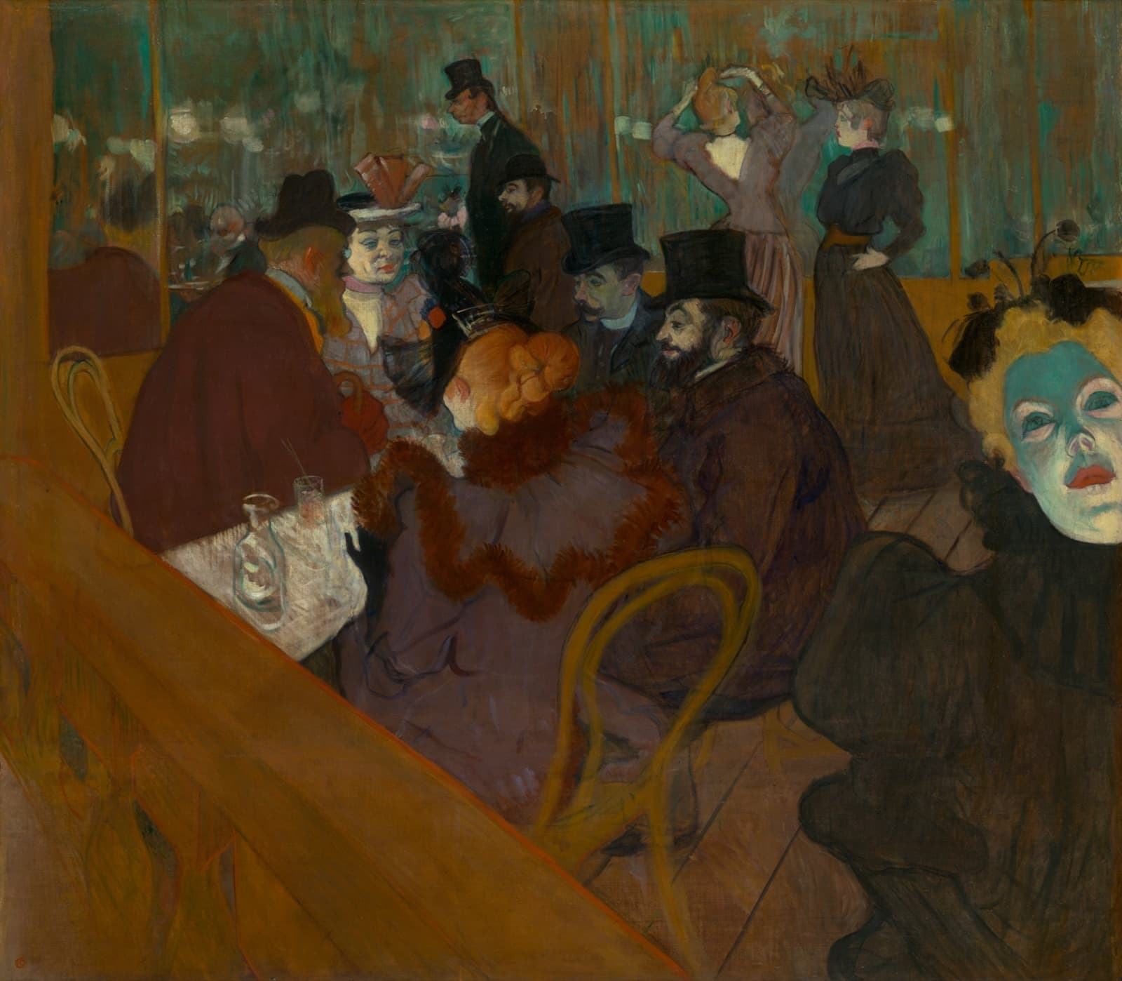 A crowded nightclub interior seen at a steep angle. Five people sit around a table in the middle distance, three of the men in top hats. A woman with red hair and a brown feather boa has her back to the viewer. At the right edge a woman's face is lit from below in harsh green. In the background two women stand before a mirror, one arranging her hair. A pale wooden balustrade cuts diagonally across the lower left corner.