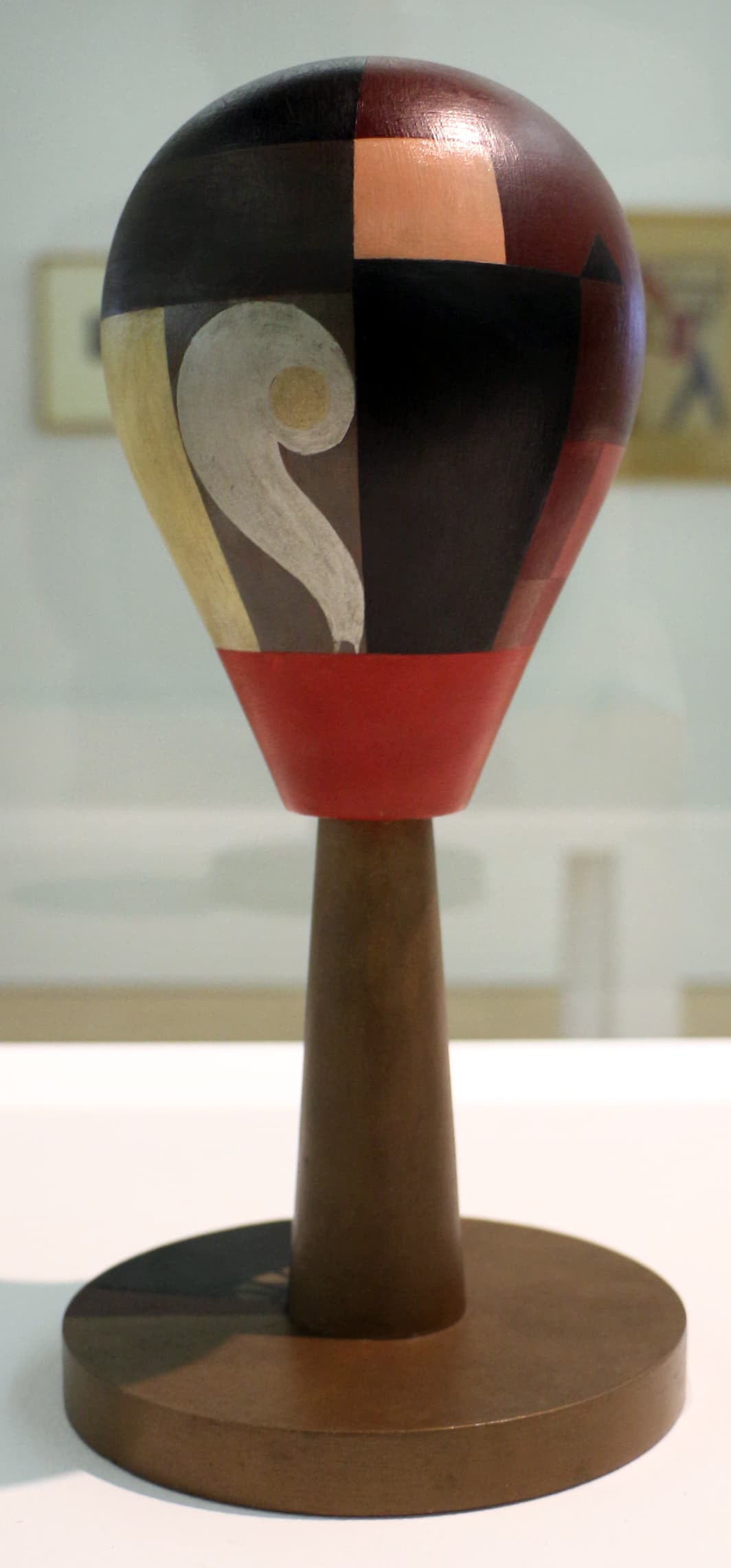 Taeuber-Arp's Dada Head: a turned wooden oval head painted with red, blue, black, white, and gold geometric forms, mounted on a slender painted base