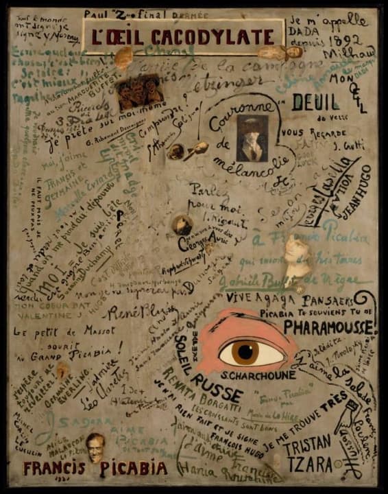 A grey canvas covered edge to edge with handwritten names, phrases and dedications in black, brown and pale green, running in every direction, with a few small photographs pasted among them. L'OEIL CACODYLATE is painted in dark red capitals on a cream plaque at the top. Near the lower right a large brown eye with a pink lid looks out. FRANCIS PICABIA 1921 is written in red capitals at the bottom left, and TRISTAN TZARA in black capitals at the bottom right