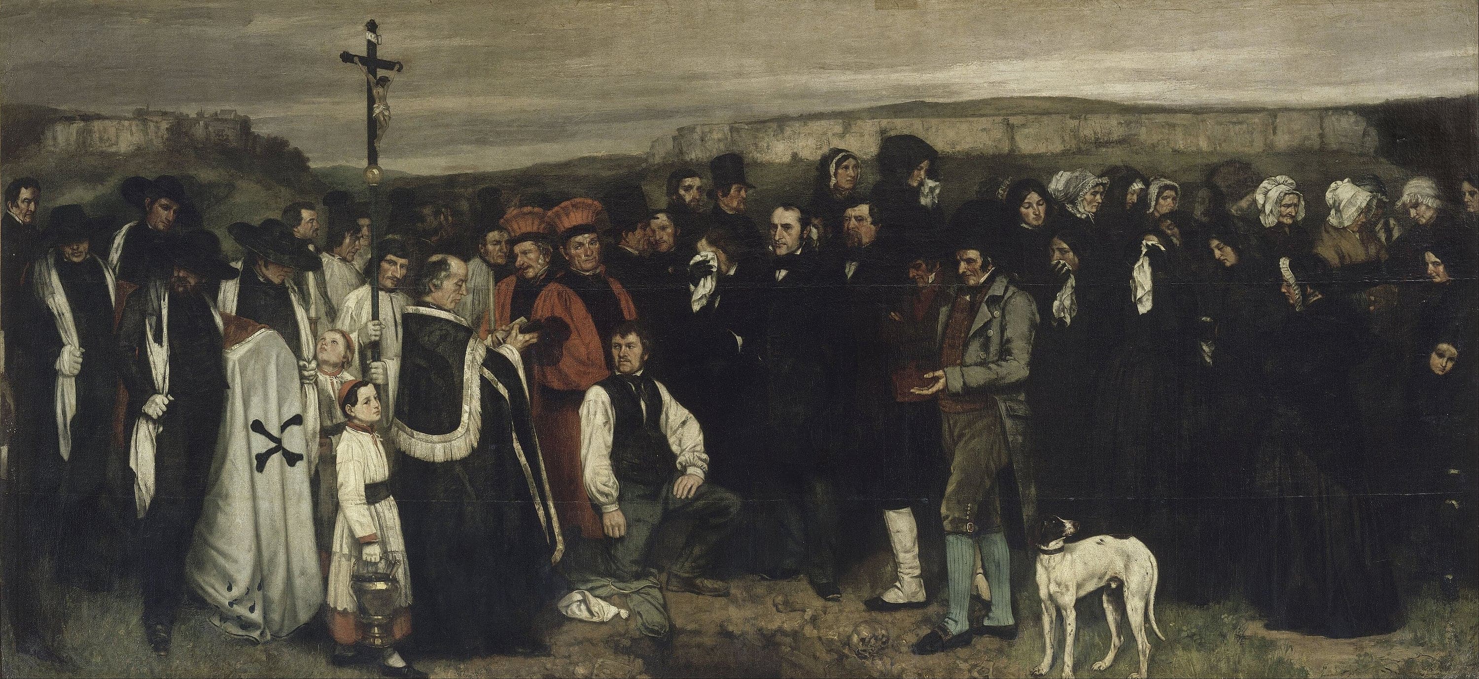 A very wide canvas showing around forty villagers standing in a long band around an open grave. Pallbearers in wide black hats and long white mourning scarves hold the far left, then the clergy with a crucifix raised on a staff and two beadles in scarlet robes, then the men of the town in black coats and hats, then a group of women weeping into handkerchiefs. A dog stands in the foreground looking away. At the centre bottom is a dark rectangular grave with a skull and bones beside the turned earth, with low limestone cliffs and grey sky behind