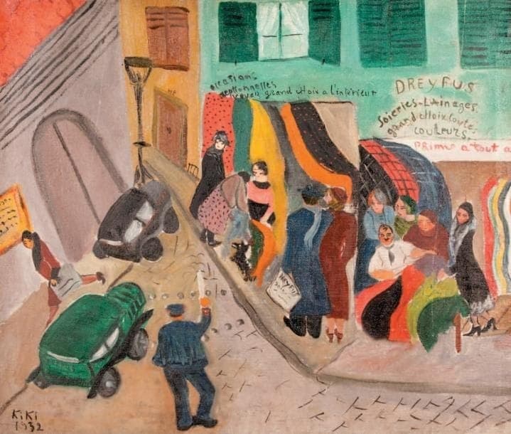 A Paris street corner seen from above. Long bolts of cloth in red with dark spots, green, yellow, grey, orange, black and cream hang from the first floor of a green-painted drapery down over the pavement. Above them the wall is lettered by hand: occasions exceptionnelles, voyez grand choix à l'intérieur, and at the right DREYFUS in large capitals with Soieries - Lainages below it. About a dozen women in coats and cloche hats press along the cloth, with a small black and white dog at the kerb. On the road at the left a policeman in a dark blue cape and flat navy cap stands with his back turned. His right arm is raised, holding a white baton with an orange tip, between a parked black car and a green van. Green shutters and an open window with a white curtain stand above the shop front