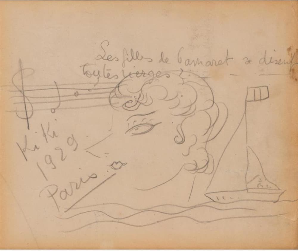A small sheet of tanned cream paper drawn on in pencil. Across the top, in handwriting, runs the line Les filles de Camaret se disent toutes vierges ? with a question mark and a ruled dash. A treble clef and a five-line stave carrying a few note heads run in from the left edge. A woman's head in profile faces left in the centre, her hair a mass of drawn ringlets with two long S-curls at the neck, one lashed eye, a narrow V of a nose and a small closed mouth. A sailing boat with a triangular sail and a tall flagged mast sits at the right on two wavy lines of sea, and the signature Kiki 1929 Paris is written in three underlined lines at the left