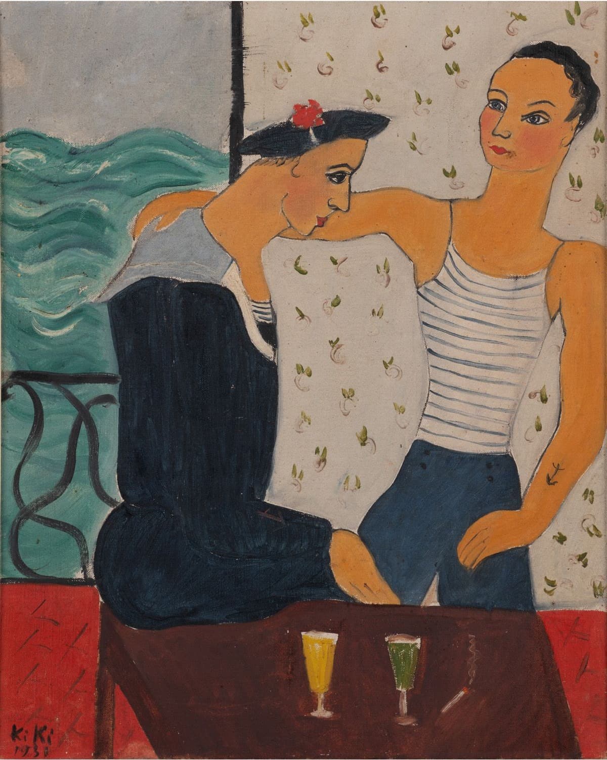 Two figures in French naval dress at a dark red-brown table. The seated one at the left leans forward with the chin on a bare orange forearm, wearing a dark navy jumper with a pale grey-blue square sailor collar and a navy cap with a red pompom on black hair. The standing one at the right has one hand on the hip and the other arm across the first figure's shoulders. That figure wears a white jersey striped in blue and dark blue buttoned trousers, with a small dark anchor tattooed on the forearm. Two tall glasses stand on the table, one filled with yellow and one with green, each with a pale head. A panel of green water with white crests fills the left background behind a black iron curve, and the wall at the right is papered with small sprigs of green leaves and pink buds