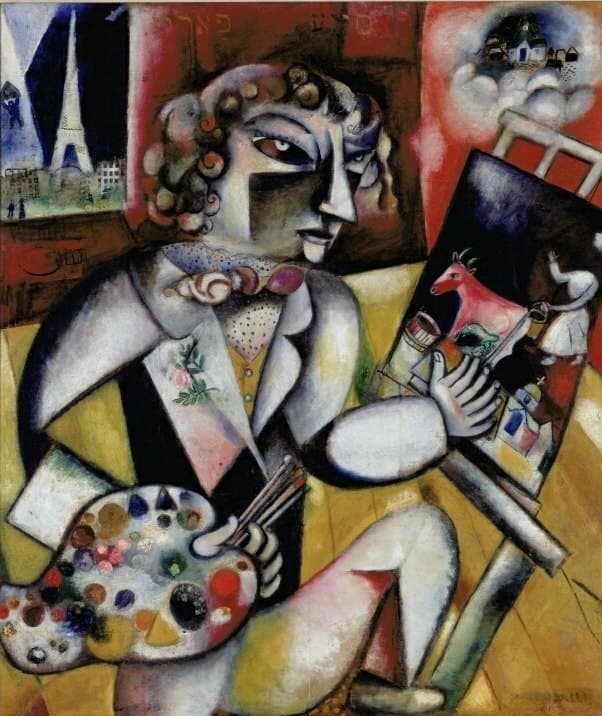 A painter in a pale suit sits three-quarters to his left at the centre of the canvas, his hair drawn as separate spiral curls and his face split by colour down the middle. Through a window at the upper left the Eiffel Tower stands against a dark blue night above a street with two small figures. At the upper right a white cloud carries a village with a white-gabled church. On the easel at his right is a painting of a red-pink horned animal with a woman in white holding a pail, and the flat white hand resting against that canvas has seven fingers. His other hand holds a fistful of brushes over a large palette dotted with colour at the lower left. The wall behind is red and the floor is yellow boards