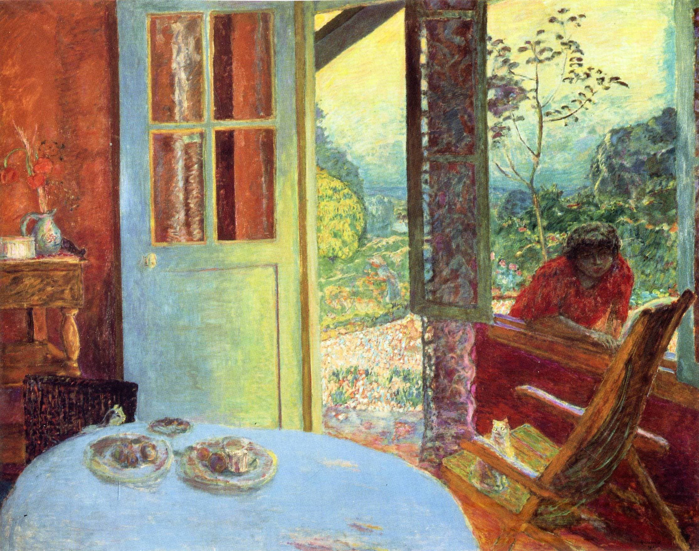 Bonnard's Dining Room in the Country: a round table under a pale blue cloth holds dishes of fruit in front of a blue-gray door and a wide open window, with a red-orange room on the left, a green garden and the hills of the Seine valley beyond, and a woman in a red blouse leaning on the sill at the right