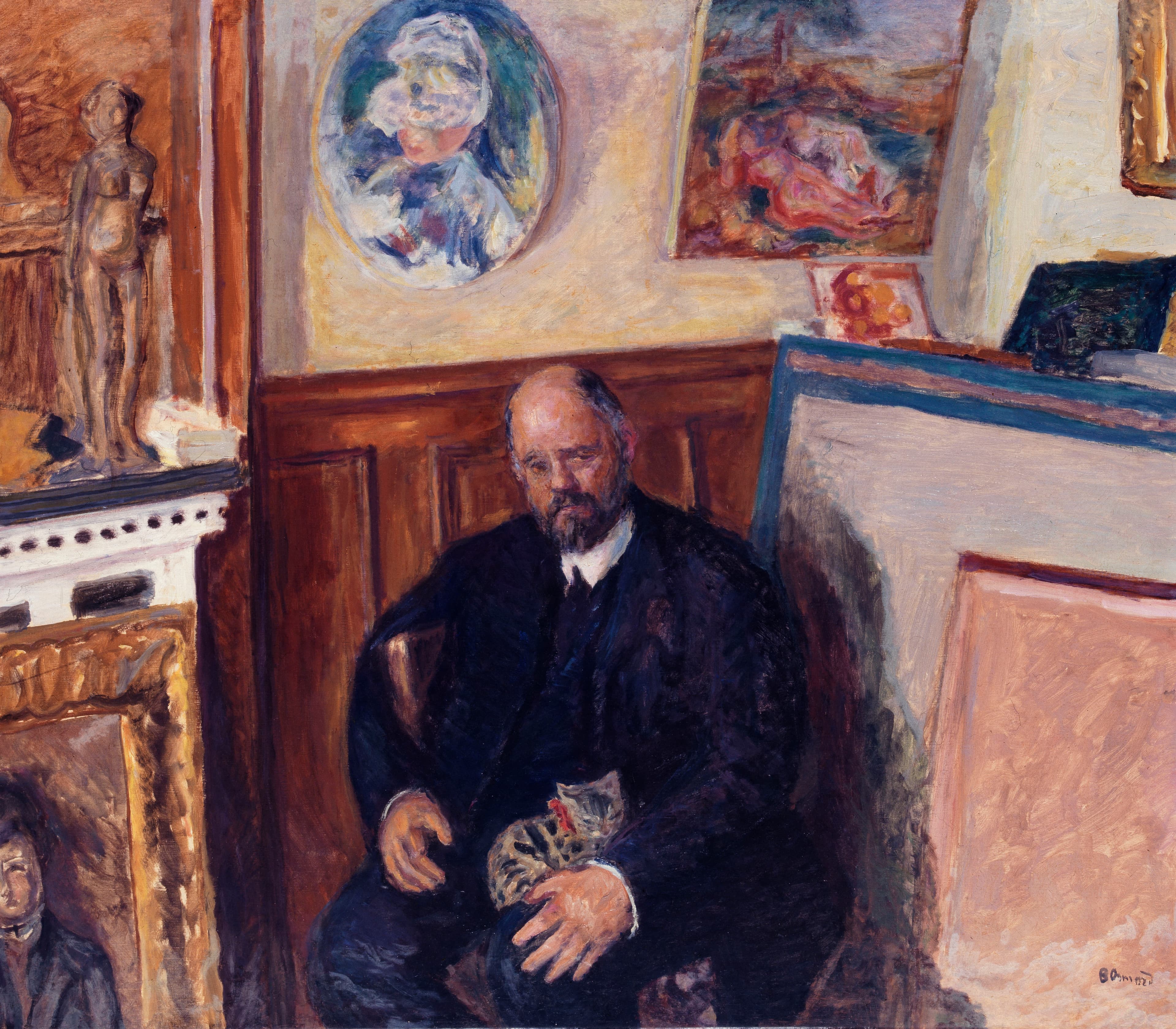 Bonnard's portrait of Ambroise Vollard: a bald, bearded man in a dark suit sits hunched with his eyes lowered and a grey-brown tabby cat on his lap, in front of brown wainscot, with framed paintings above him and large blank canvases in grey-lilac and salmon-pink stacked at the right