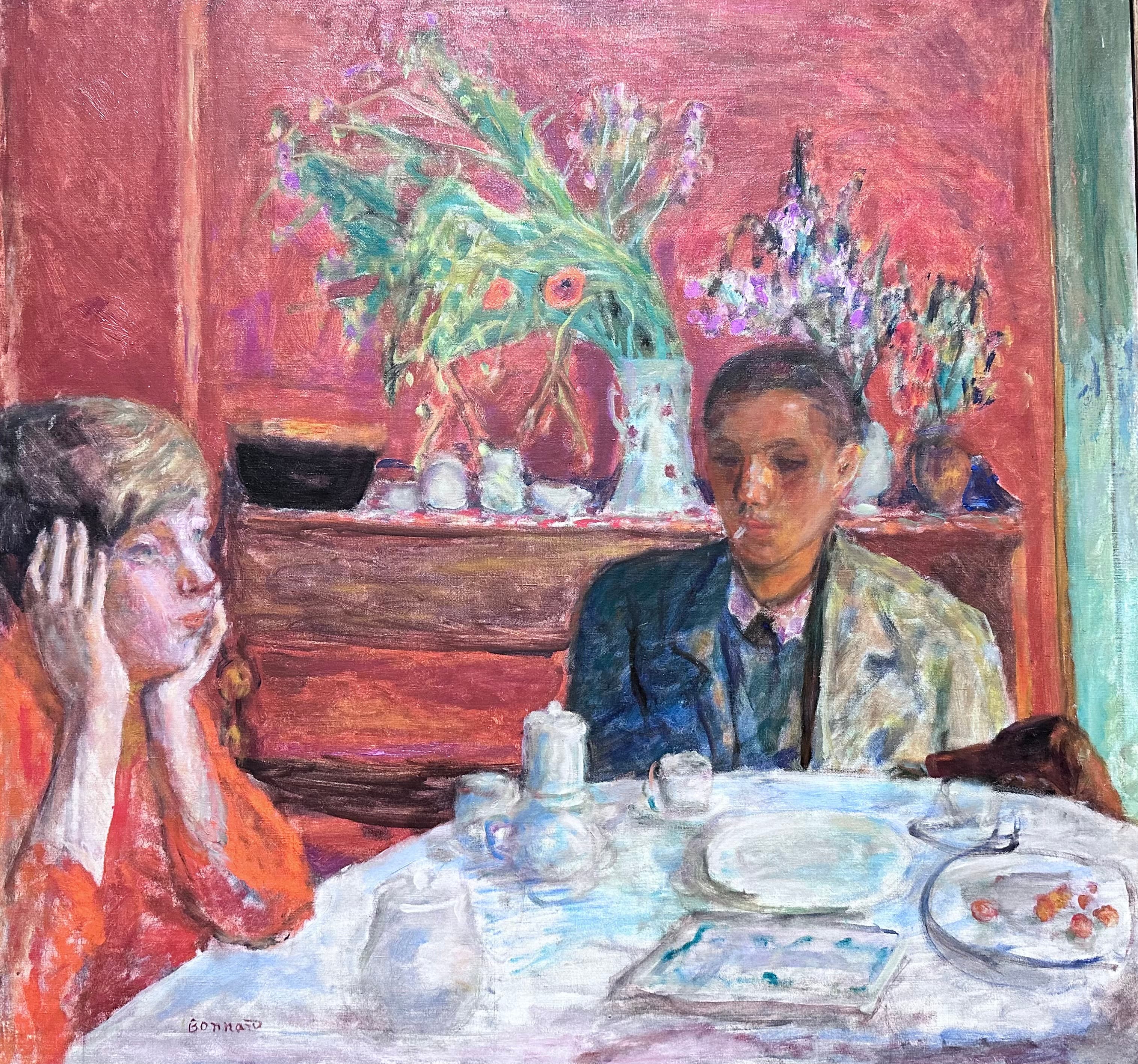 Bonnard's The Dessert: a woman in orange holds her head in both hands at the left of a white-clothed table while a young man with a cigarette sits at the right, a coffee pot between them, a white dish of small orange-red fruits and a dog's head at the right, and two bouquets on a sideboard against a rose-red wall