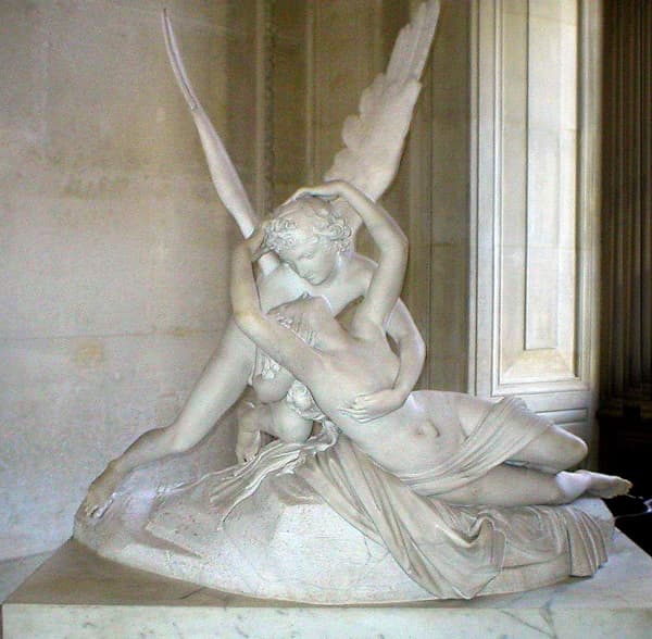 Canova's marble of winged Cupid holding the waking Psyche, her raised arms reaching to his head, on a rocky base