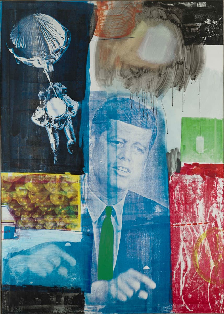 A tall canvas crowded with silkscreened photographs and brushed paint. In the centre John F. Kennedy is printed in blue on a blue ground, head and shoulders, mouth open, his right hand raised at the bottom with the index finger extended, and a block of solid green paint laid over his tie. At the upper left a dark navy panel carries a white and pale blue image of a parachute canopy above a figure in a pressure suit with a spherical pack on the chest. A broad grey-brown arc brushed in loops with black drips crosses the top centre, and a black-and-white photograph of scaffolding at the top right shows a man in a white hard hat and a checked jacket twice over. A yellow-bordered rectangle at the left holds a heaped mass of round fruit, a green rectangle at the right carries the pale outline of a full drinking glass, and a scraped red field with a loose yellow circle fills the lower right