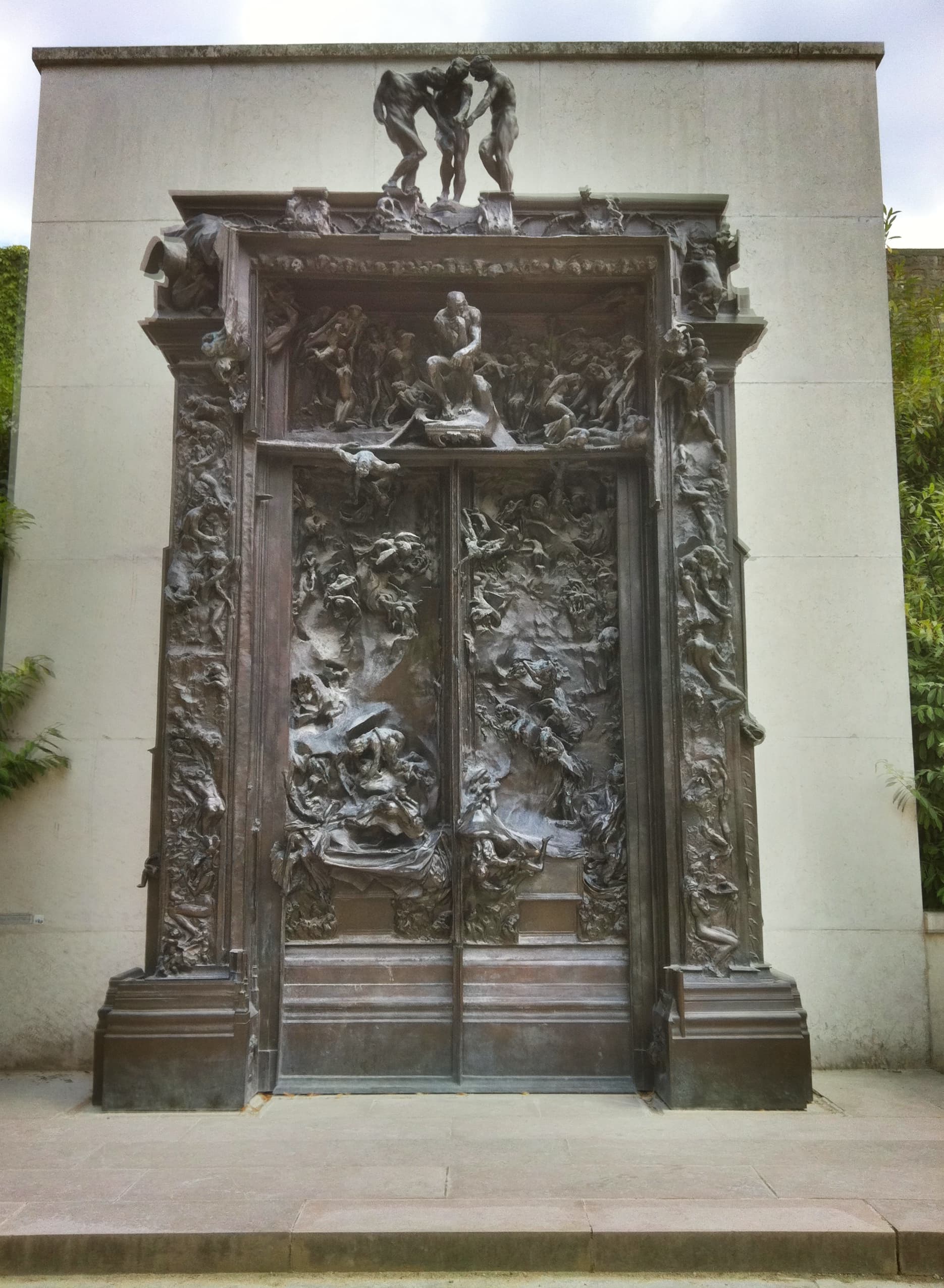 Auguste Rodin's monumental bronze Gates of Hell in the Musée Rodin garden in Paris, covered with falling and twisting human figures beneath The Thinker and The Three Shades