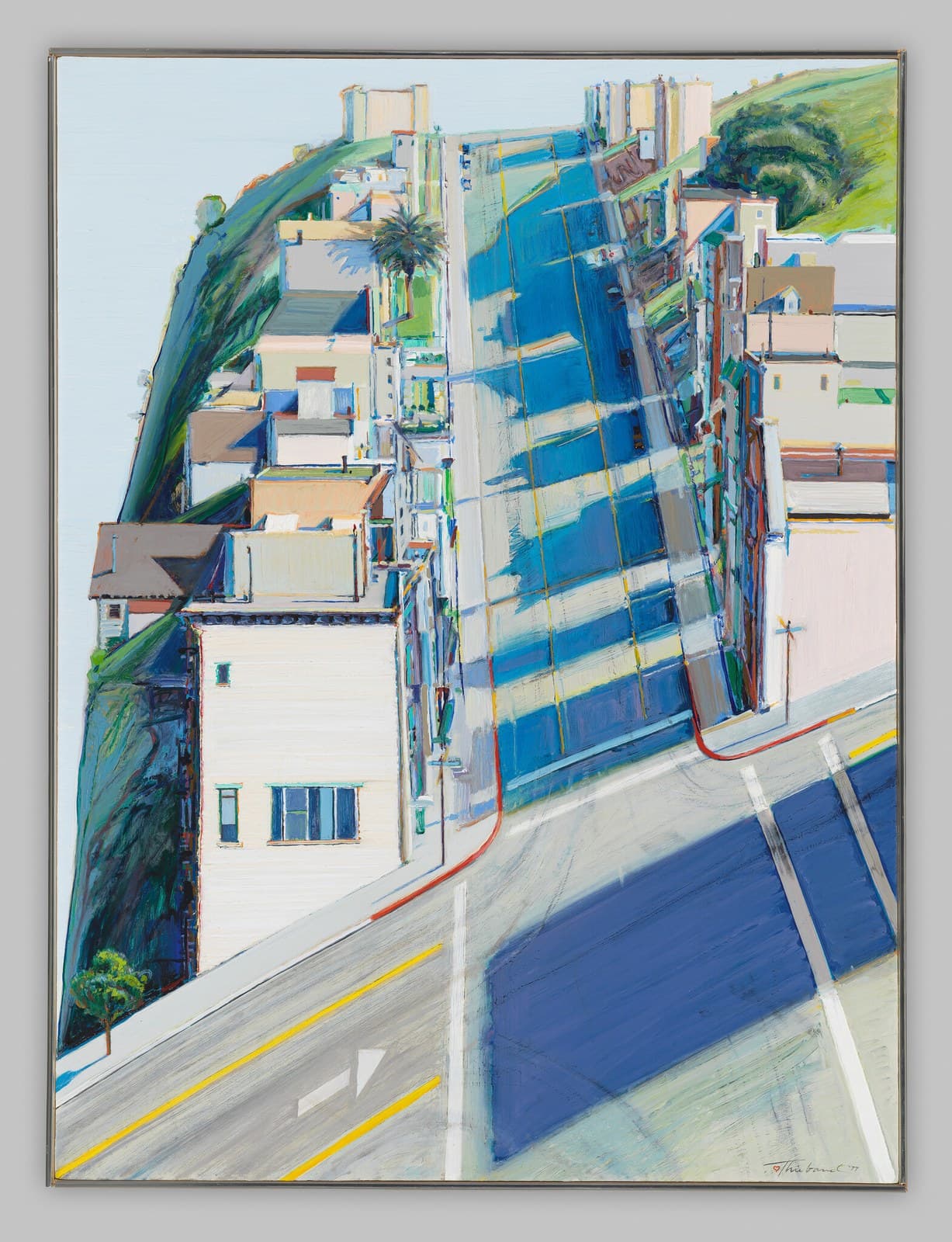 A street rising almost vertically up the centre of a tall canvas, painted as a broad band of blue and grey-green with a thin yellow line up the middle and a red kerb line along its left side. In the foreground a wide crossing seen from above carries a flat ultramarine shadow. A cream clapboard building with green-framed windows stands at the left below a hillside painted in teal and violet, a palm tree rises halfway up, and pale tower blocks and a green hill close the top. The painting is photographed in its thin metal frame against a grey wall