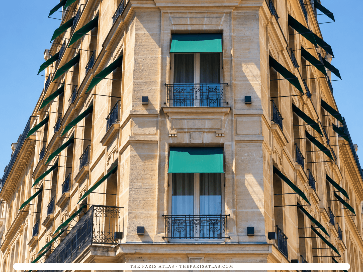 AI-generated illustration of Le Metropolitan's corner façade on place de Mexico, seen from below: honey-colored stone, wrought-iron balconies and green awnings over the windows against a blue sky.
