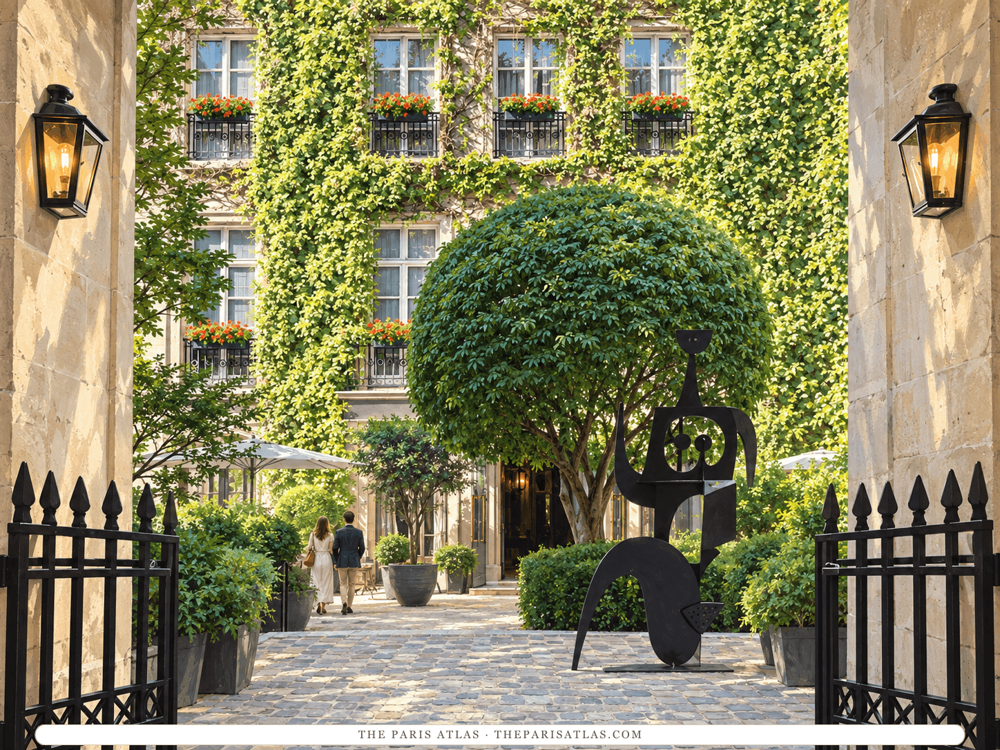 Reference-based illustration of the courtyard entrance of Le Pavillon de la Reine: open iron gates between stone walls with lanterns, leading to a cobbled courtyard with a round clipped tree, a black abstract sculpture and an ivy-covered façade with red window boxes.