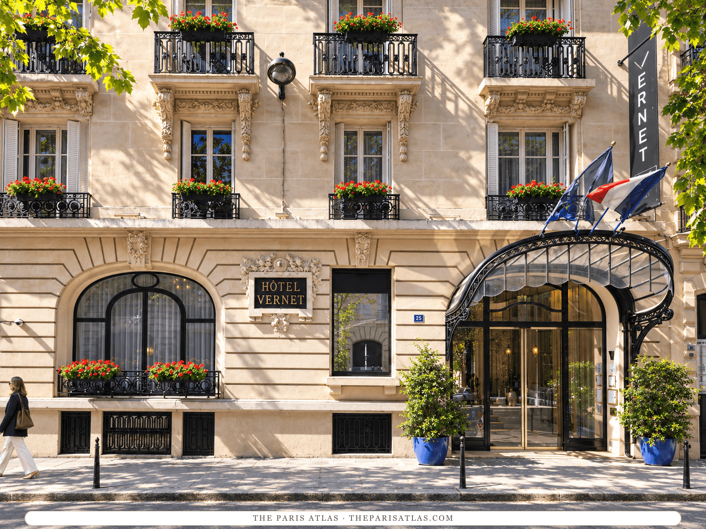 Reference-based illustration of the stone front of Hôtel Vernet: a plaque reading Hôtel Vernet, a curved iron-and-glass canopy over the entrance with French and European flags, a vertical Vernet sign, blue planters and red window boxes.