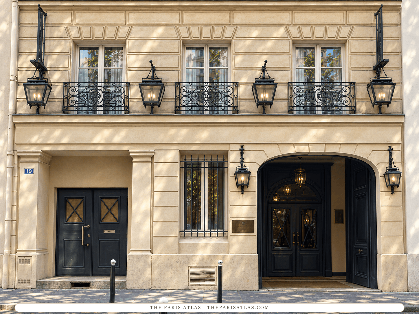 Reference-based illustration of the cream stone front of Maison Athénée at number 19, with a black arched carriage entrance on the right, a black double door on the left, lanterns on the walls and three wrought-iron balconies above.