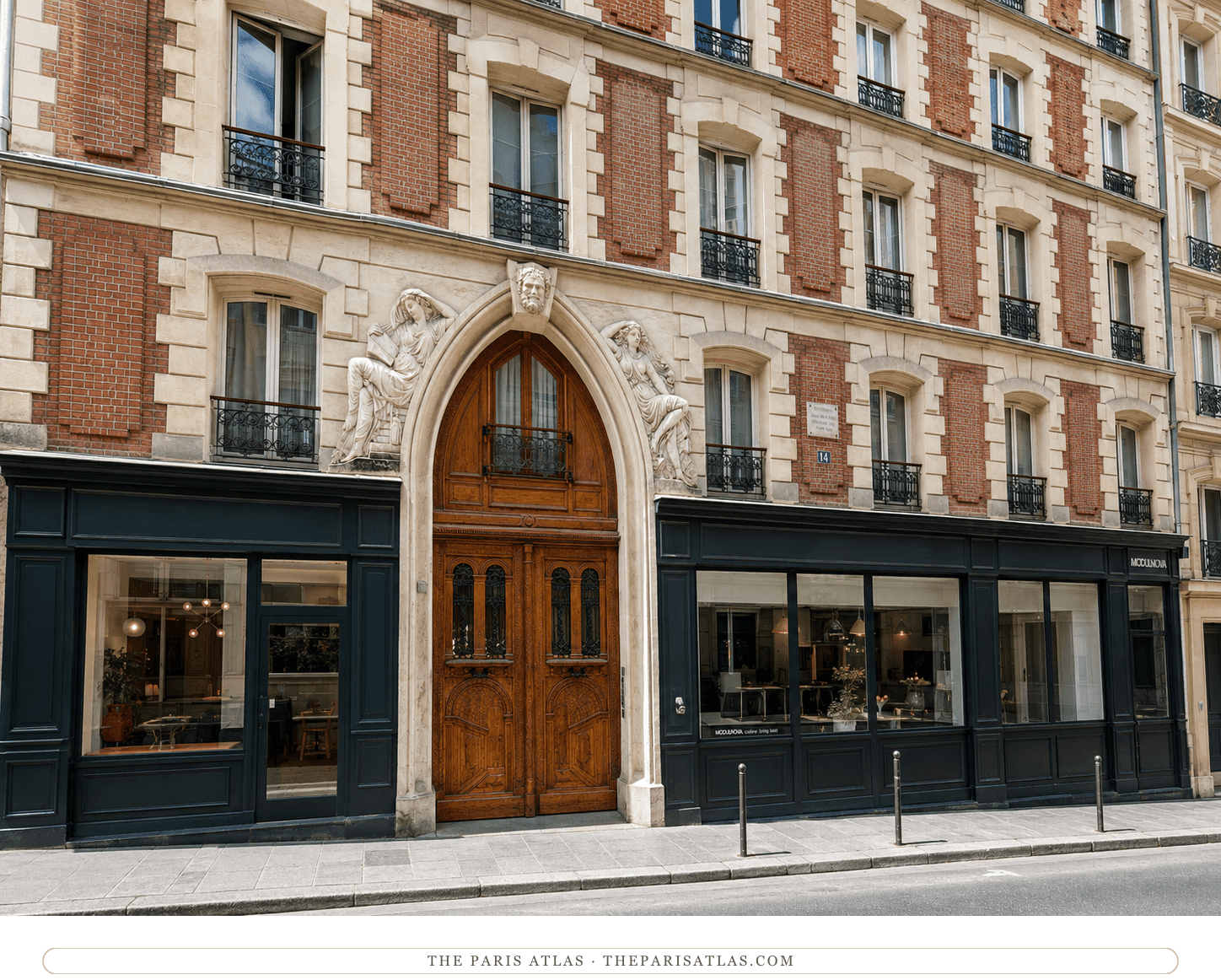 14 rue Monsieur-le-Prince in color, brick and cream stone above dark green shopfronts, the carved oak doors under the sculpted arch in summer light