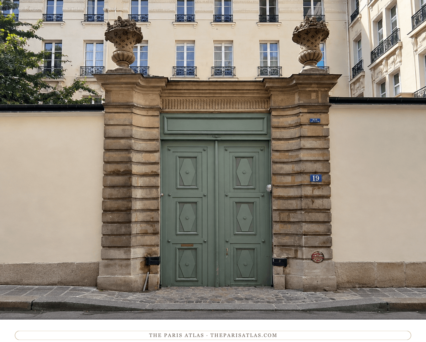 The same entrance at 19 rue de Lille in colour, pale green doors between honey-coloured stone piers with carved urns above