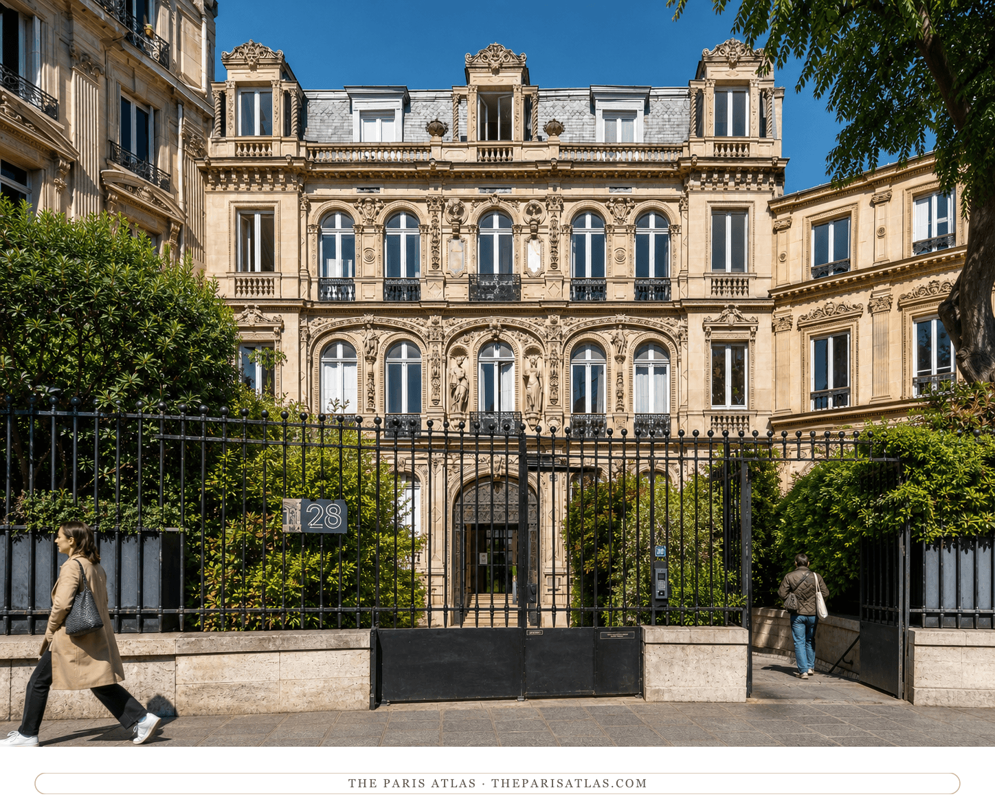 Color view of the ornate stone façade, garden and iron fence at 28 place Saint-Georges in Paris