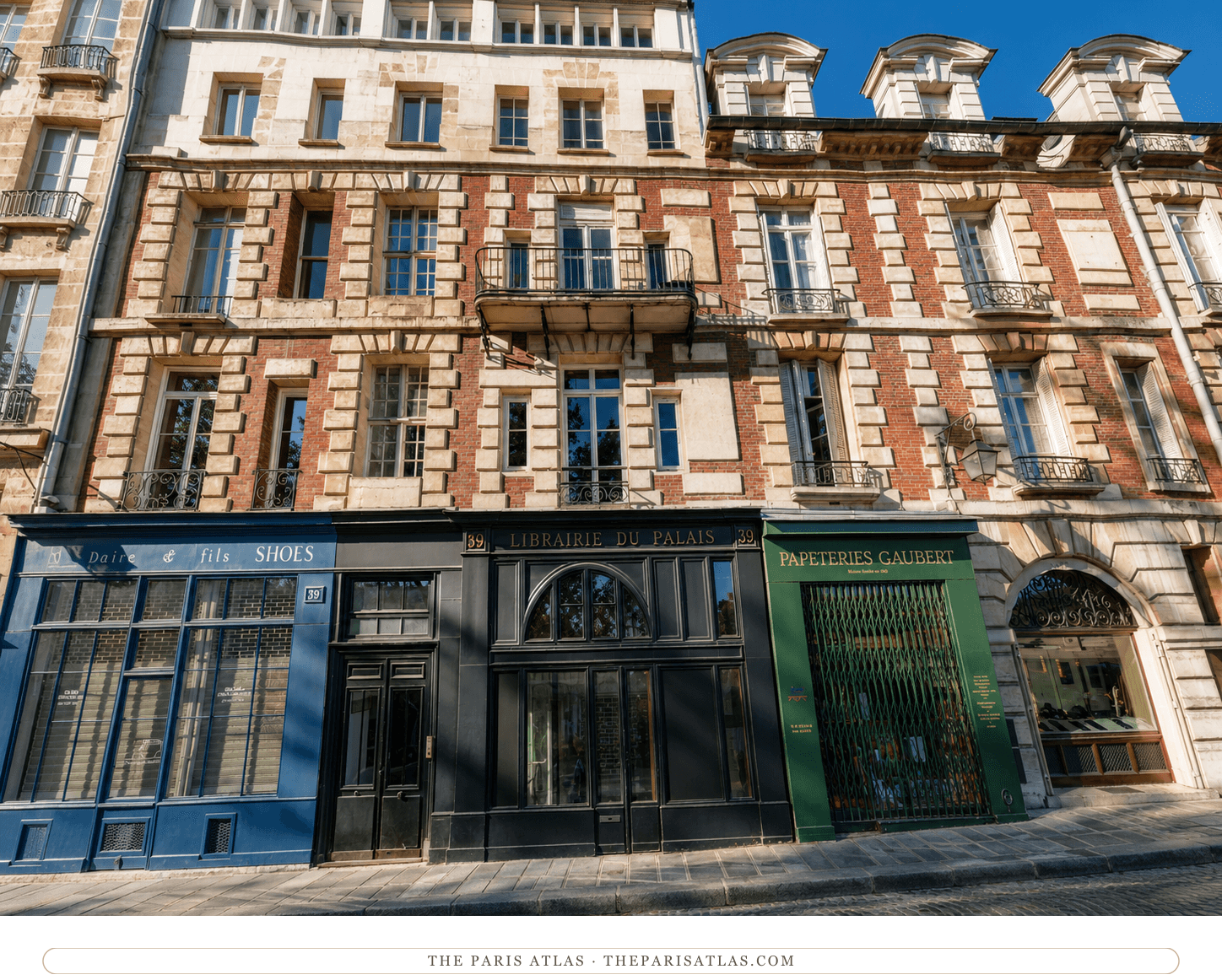 The same façade in colour, red brick and pale stone above a blue shoe shop, a black bookshop front and a green stationer's