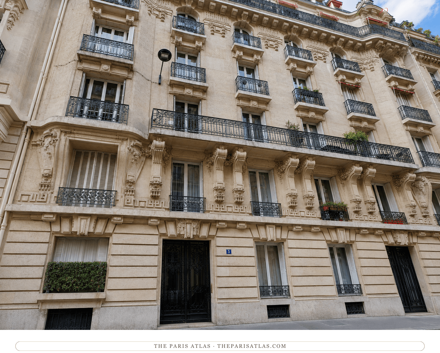 The 5 rue José-Maria-de-Heredia facade in color, pale limestone under a blue sky, black ironwork door and window boxes