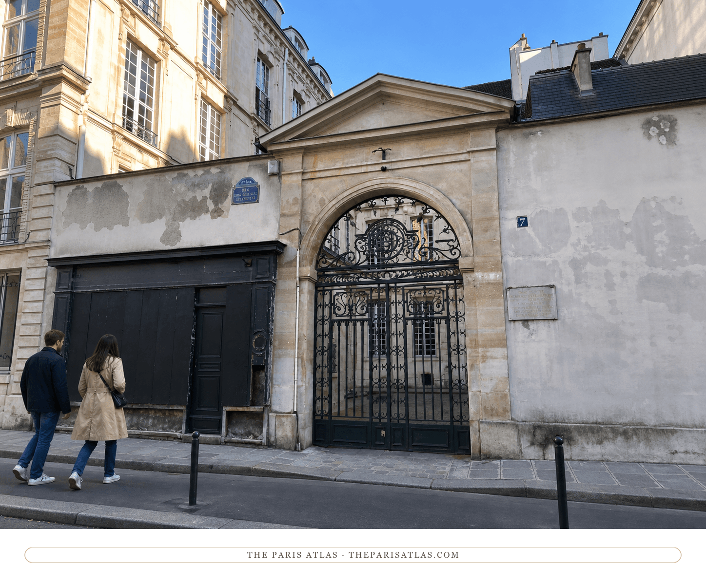 Color street view of the limestone arch and ornate dark gate at 7 rue des Grands-Augustins