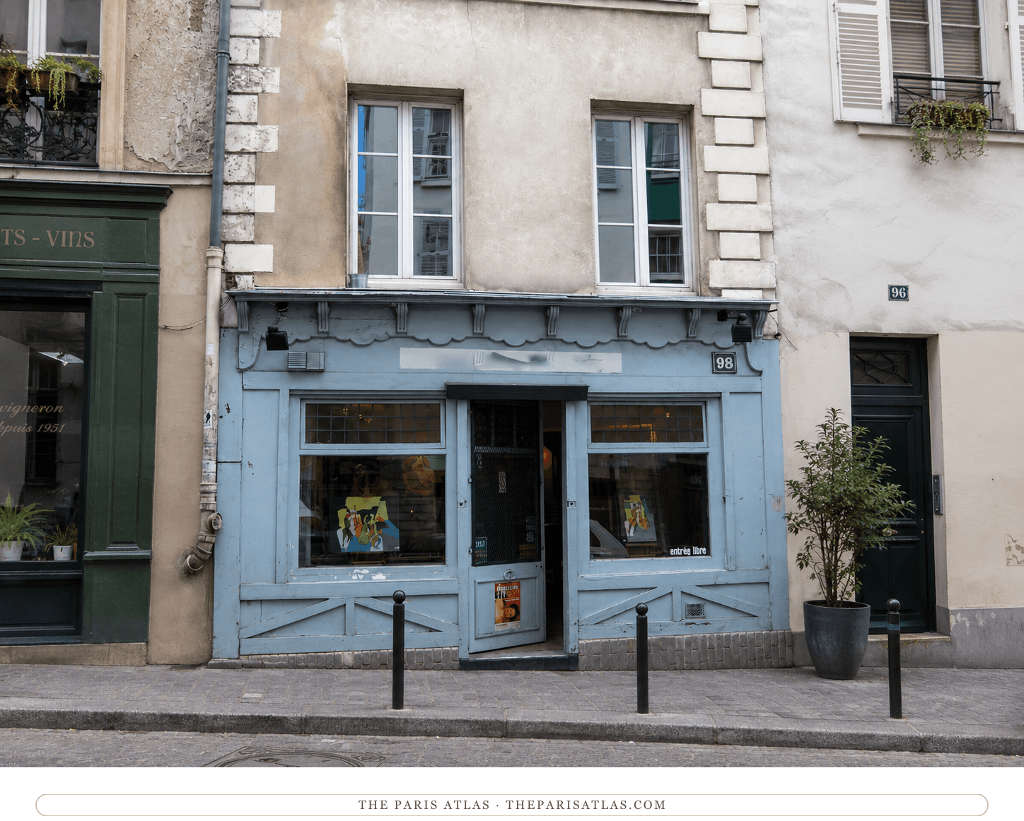 The blue-painted shopfront at 98 rue Lepic today, with the apartment windows above and number 96 alongside