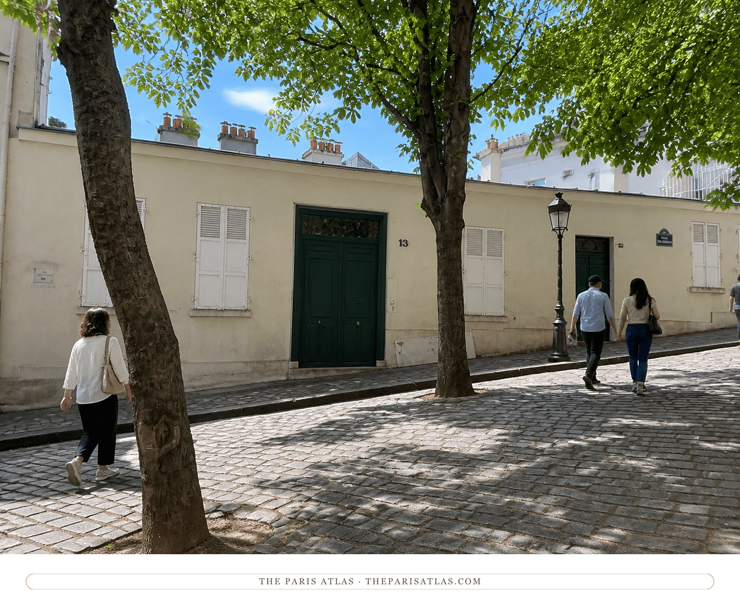 Sunlit present-day view of the pale Bateau-Lavoir façade and green doors on place Émile-Goudeau