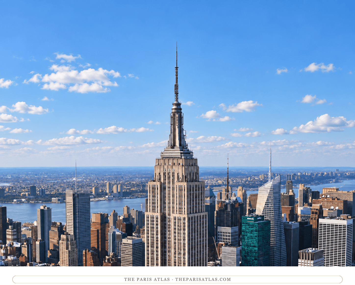 Empire State Building upper tower and antenna in bright daylight, with Midtown and the Hudson River behind