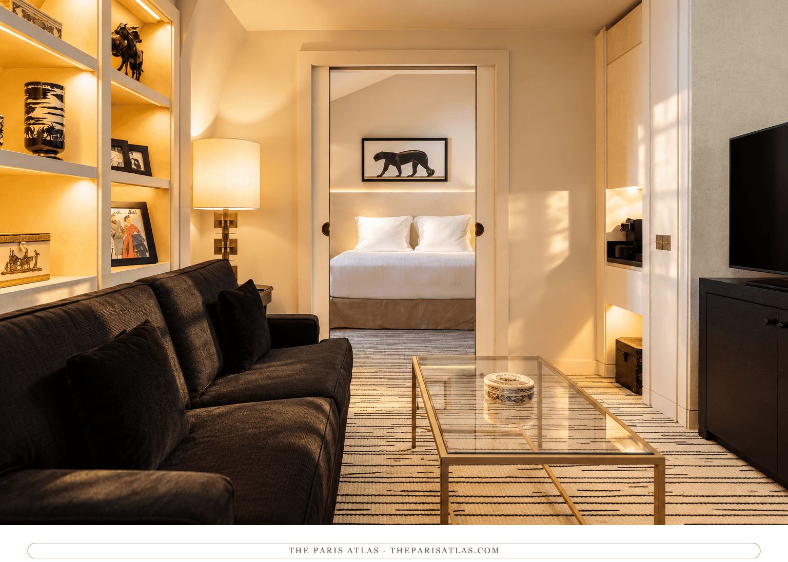 Photorealistic illustration of the Montaigne Suite, with a charcoal sofa, illuminated ivory shelves and a sliding doorway to the bedroom.