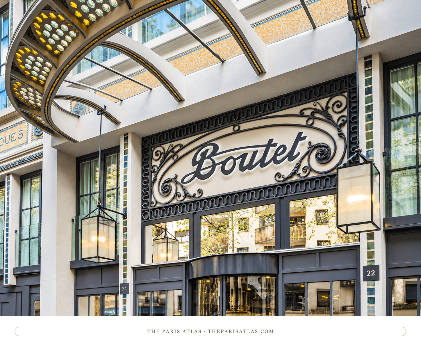 Illustration of the Boutet script sign above glass entrance doors, framed by lanterns, green tiles and a curved glass canopy.