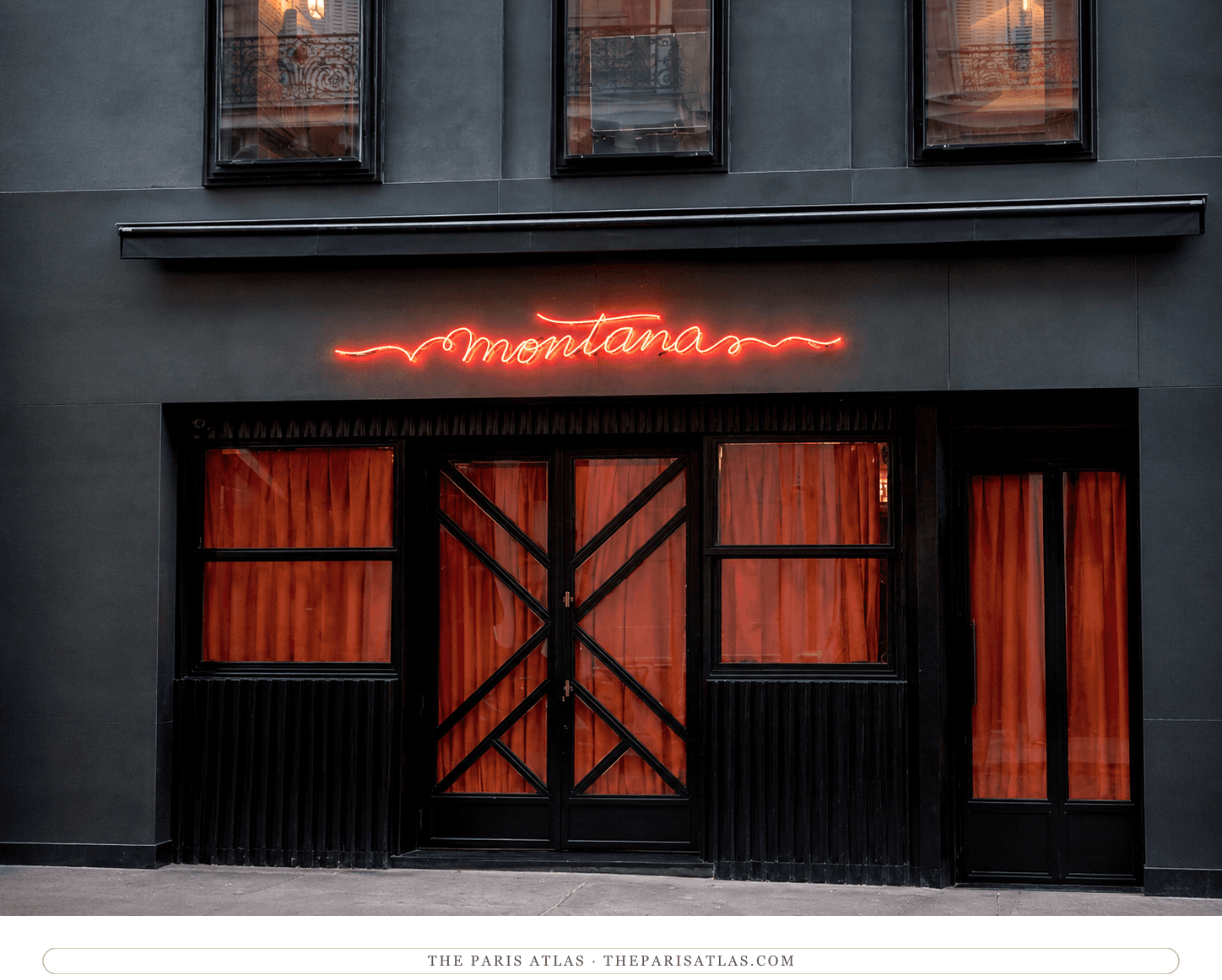 The Montana today, dark grey façade with a red cursive neon sign and red curtains behind black window frames