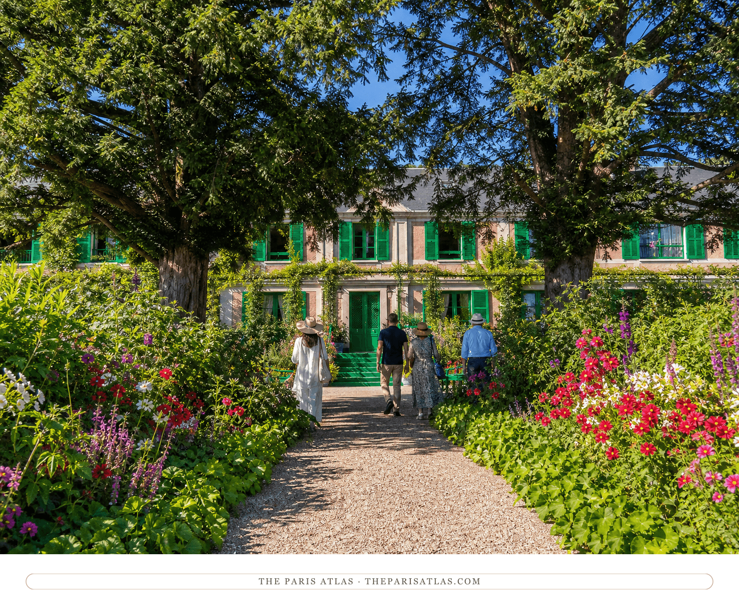 Claude Monet's pink house with green shutters beyond the flower-lined central path at Giverny