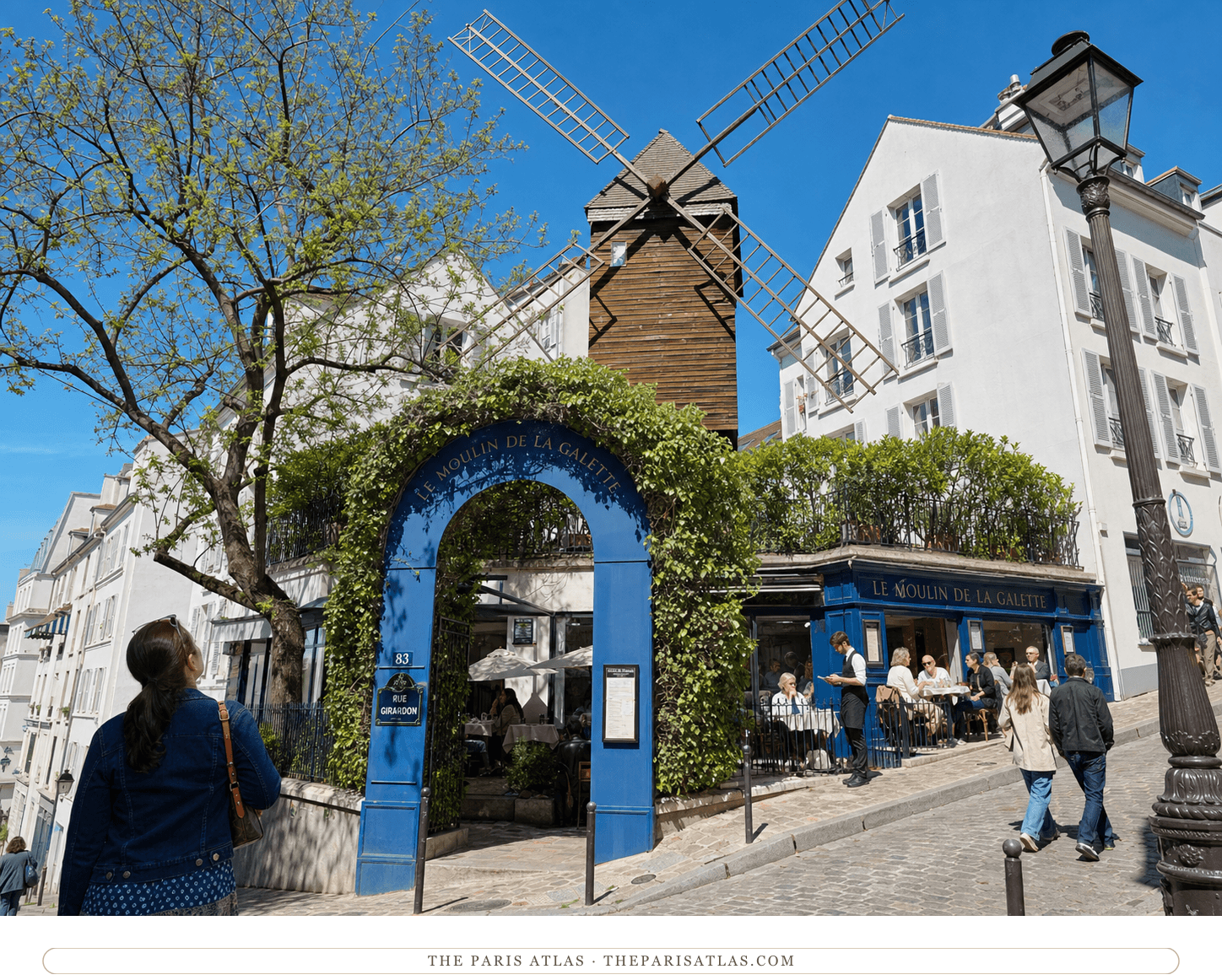 Bright present-day color view of the Moulin de la Galette windmill, blue entrance and terrace