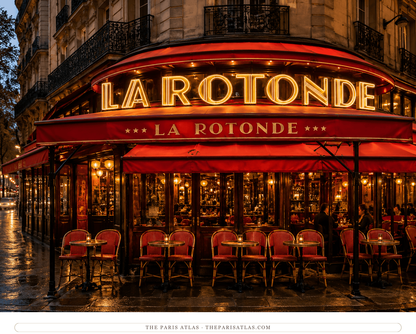 La Rotonde at night, red awnings and glowing red neon over a terrace of red-backed chairs on a wet pavement
