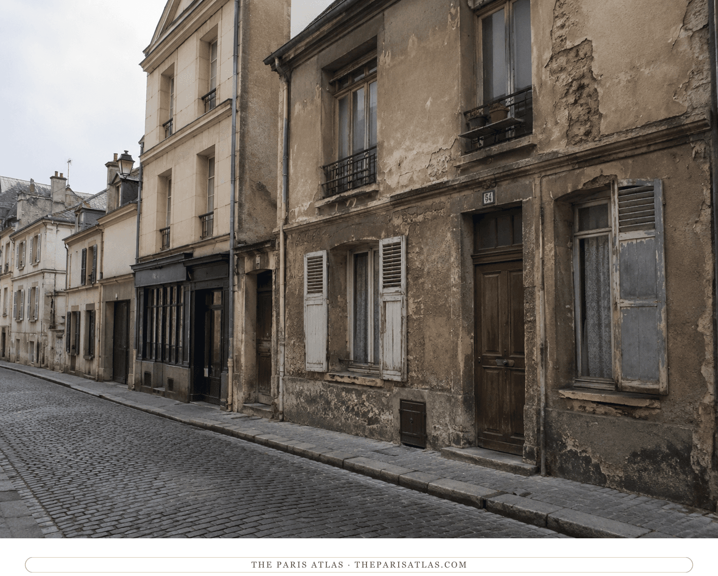 The Rue du Château in flat gray light, weathered façades and shuttered fronts along the cobbled pavement