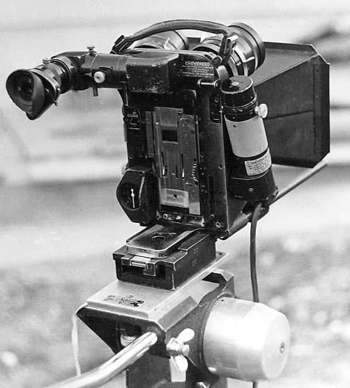 Rear view of an Éclair Cameflex 35 mm camera on a tripod, magazine and viewfinder visible, in black and white