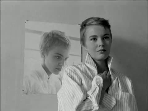 Jean Seberg standing beside a large photographic portrait of her own face