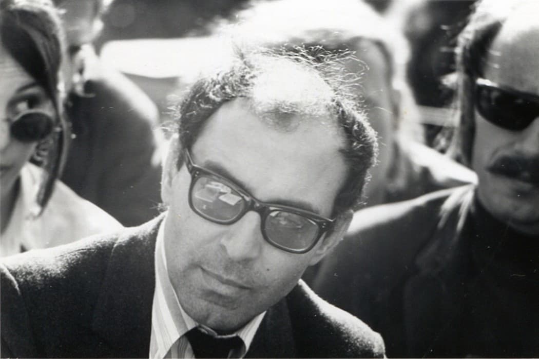 Jean-Luc Godard in dark-framed glasses surrounded by a crowd outdoors at Berkeley in 1968