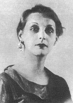 June Miller around 1933, dark-eyed with a drop earring, hair cropped short, in a halftone reproduction of Brassaï's portrait.